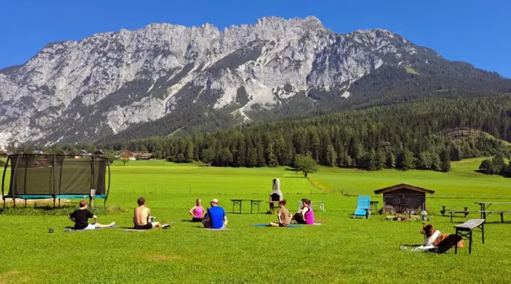 Yoga in den Bergen: „Judith leitet eine Berg-Yoga-Session im Almdorf im Winkl mit atemberaubendem Alpenpanorama.“ Freiluft Yoga im Almdorf: „Teilnehmer praktizieren Yoga im Freien, umgeben von der Schönheit der Schladming Dachstein-Berge.“ Yoga im Freien: „Entspannte Yoga-Übung inmitten der Natur des Almdorf im Winkl, mit Judith als erfahrene Yoga-Lehrerin.“